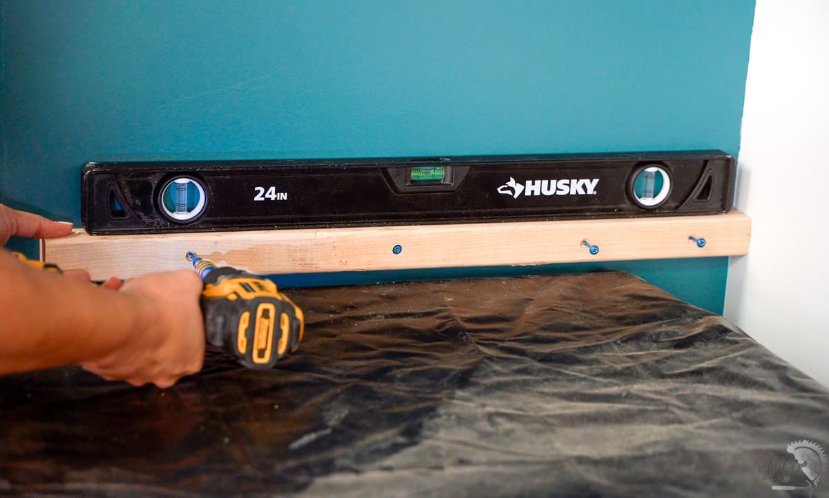 Woman attaching a 2x2 to the laundry room cabinet