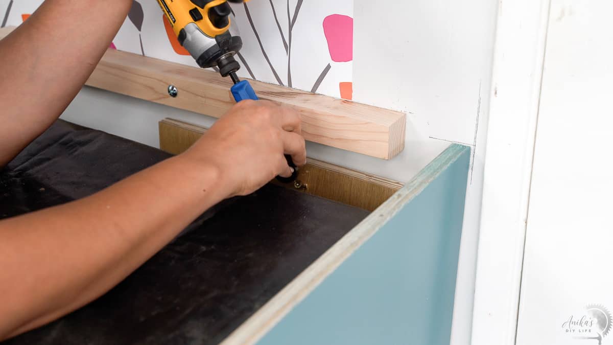 Attaching the side support to the wall using long screws.