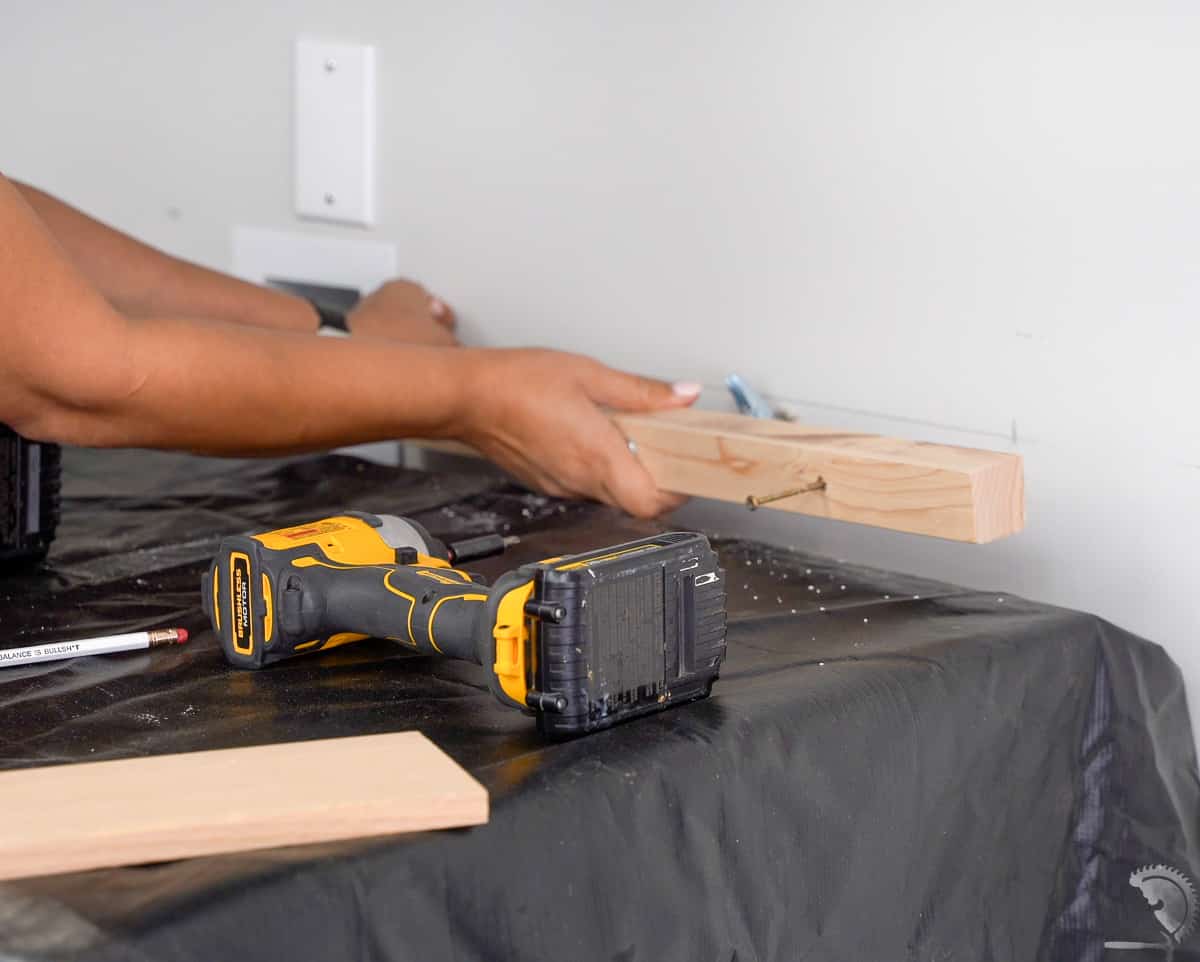 woman using toggle bolts to attach 2x2 braces for wooden countertop
