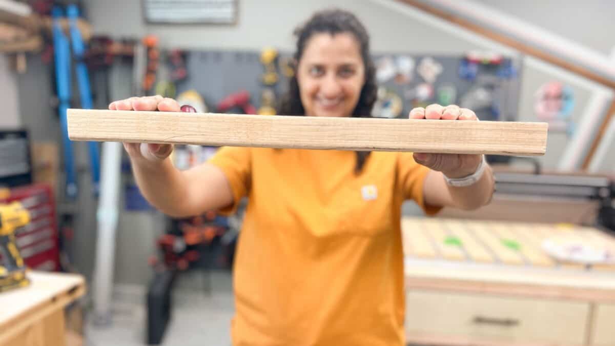 woman holding a 2x4 board in a workshop