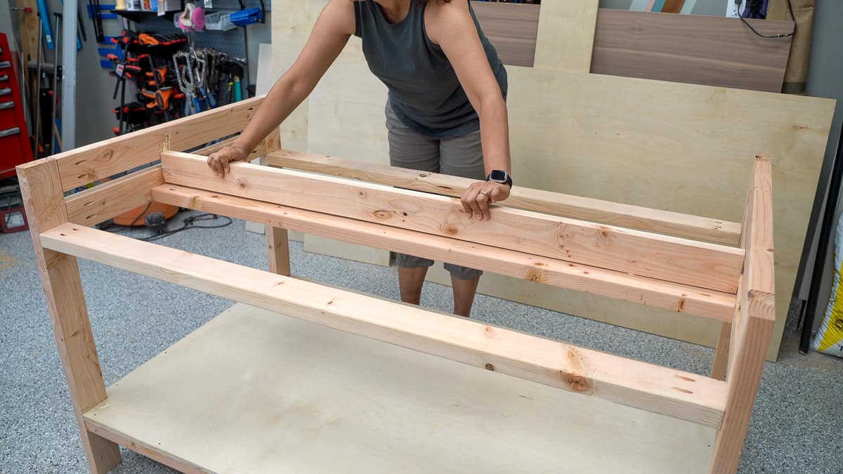 WOman attaching aprons and dividers using pocket hole screws to a workbench