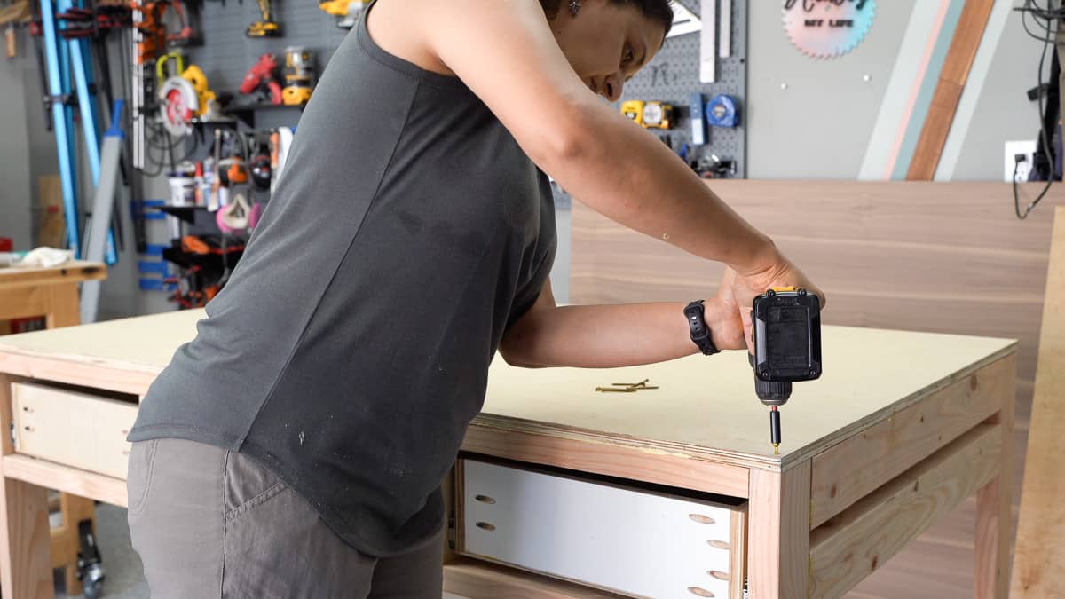 Woman attaching the workbench top with screws