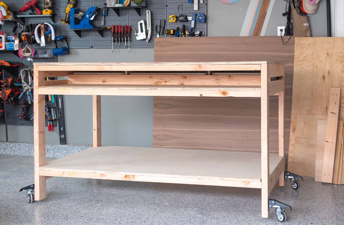 Back of the wooden workbench showing narrow shelf on top and full shelf on bottom
