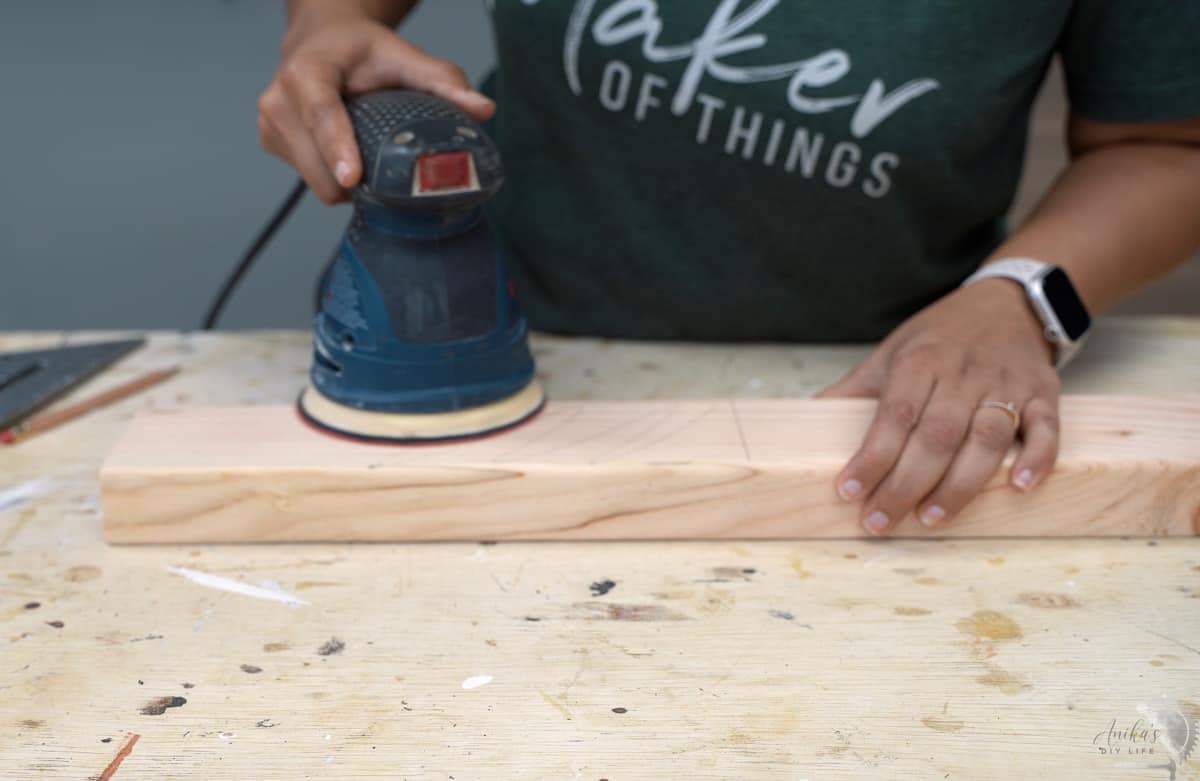 woman sanding a 2x4 with a random orbital sander