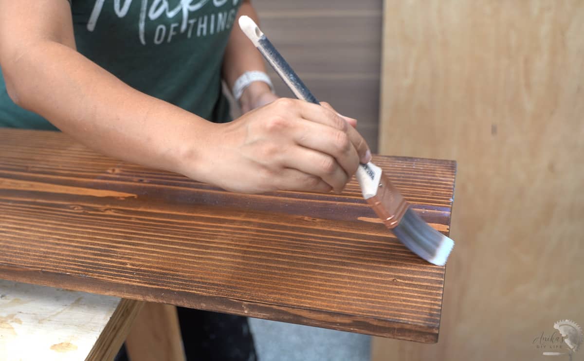 Woman applying sealer on stained wood.