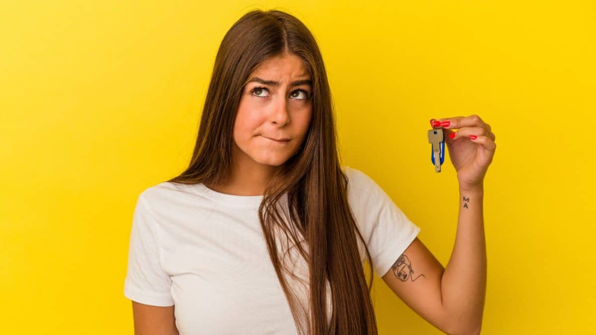 Woman holding keys with yellow background