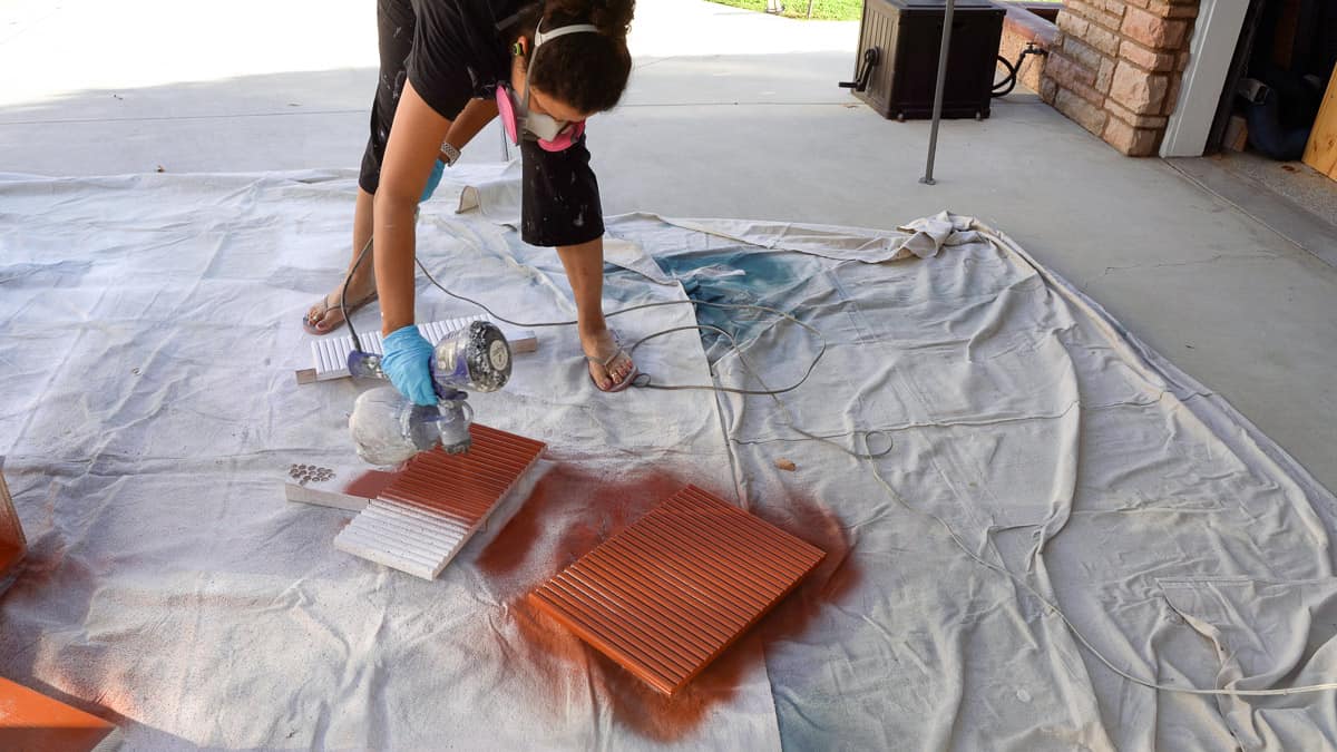 Woman painting drawer front using a paint sprayer