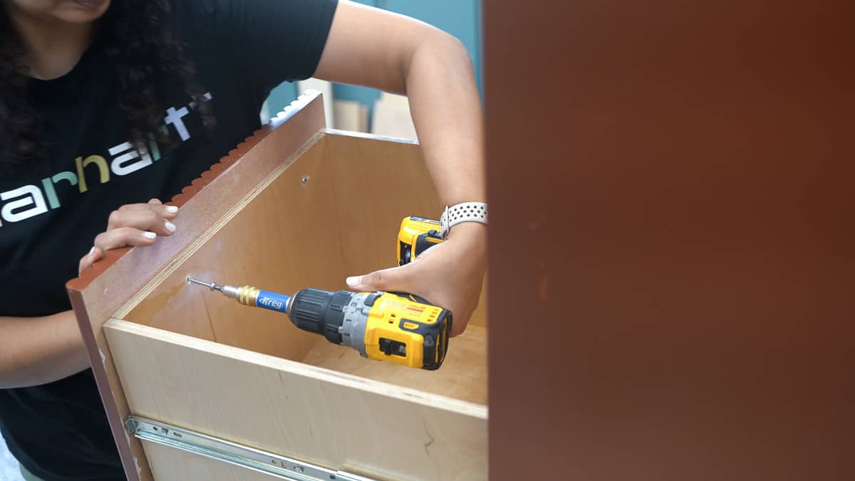 Woman attaching the drawer front on the wooden diy file cabinet