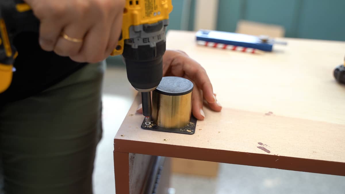 Woman attaching feet to the wooden file cabinet