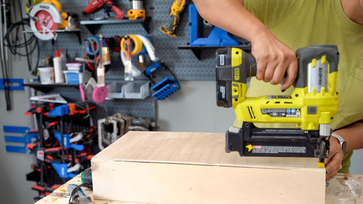 Woman building a drawer by attaching the bottom using staple gun