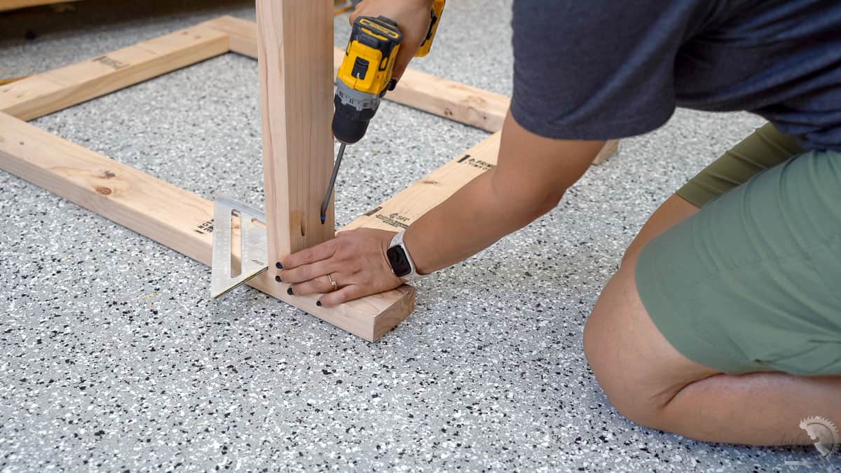 woman attaching 2x4 board to workbench legs using pocket hole screws