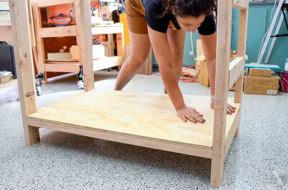 Woman placing a plywood shelf in the workbench