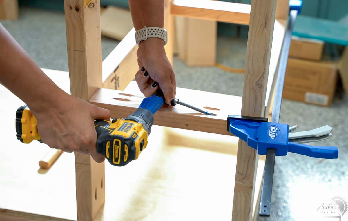 woman attaching board to DIY workbench using right angle adapter and pocket hole screws