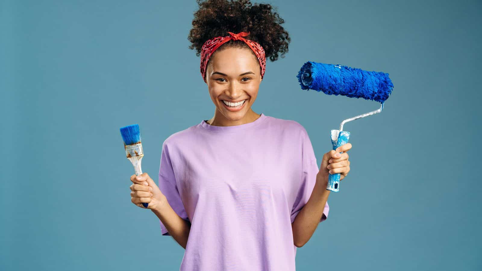 young woman with paint roller and paint brush