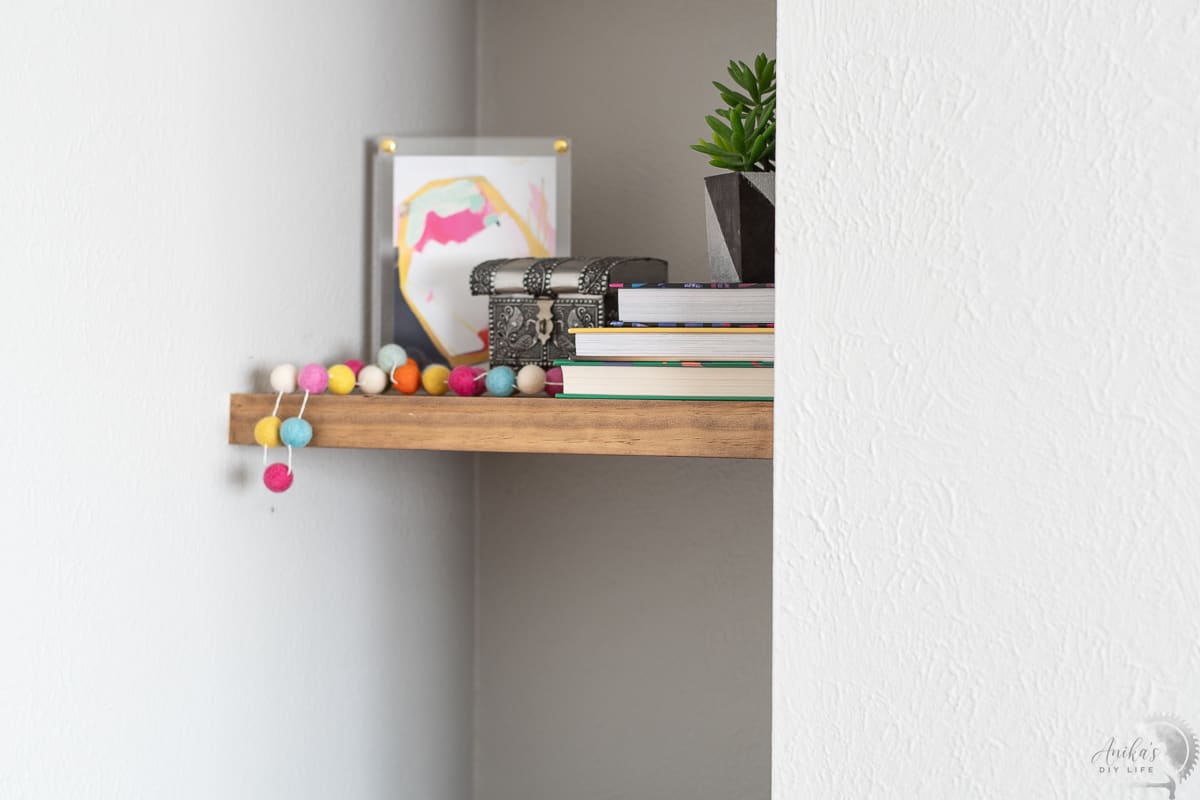close up of one of the two floating shelves in a nook with books and decor