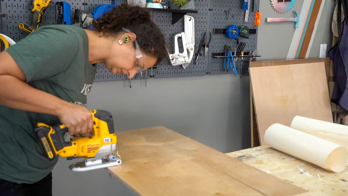 Woman cutting floating shelf plywood using jigsaw