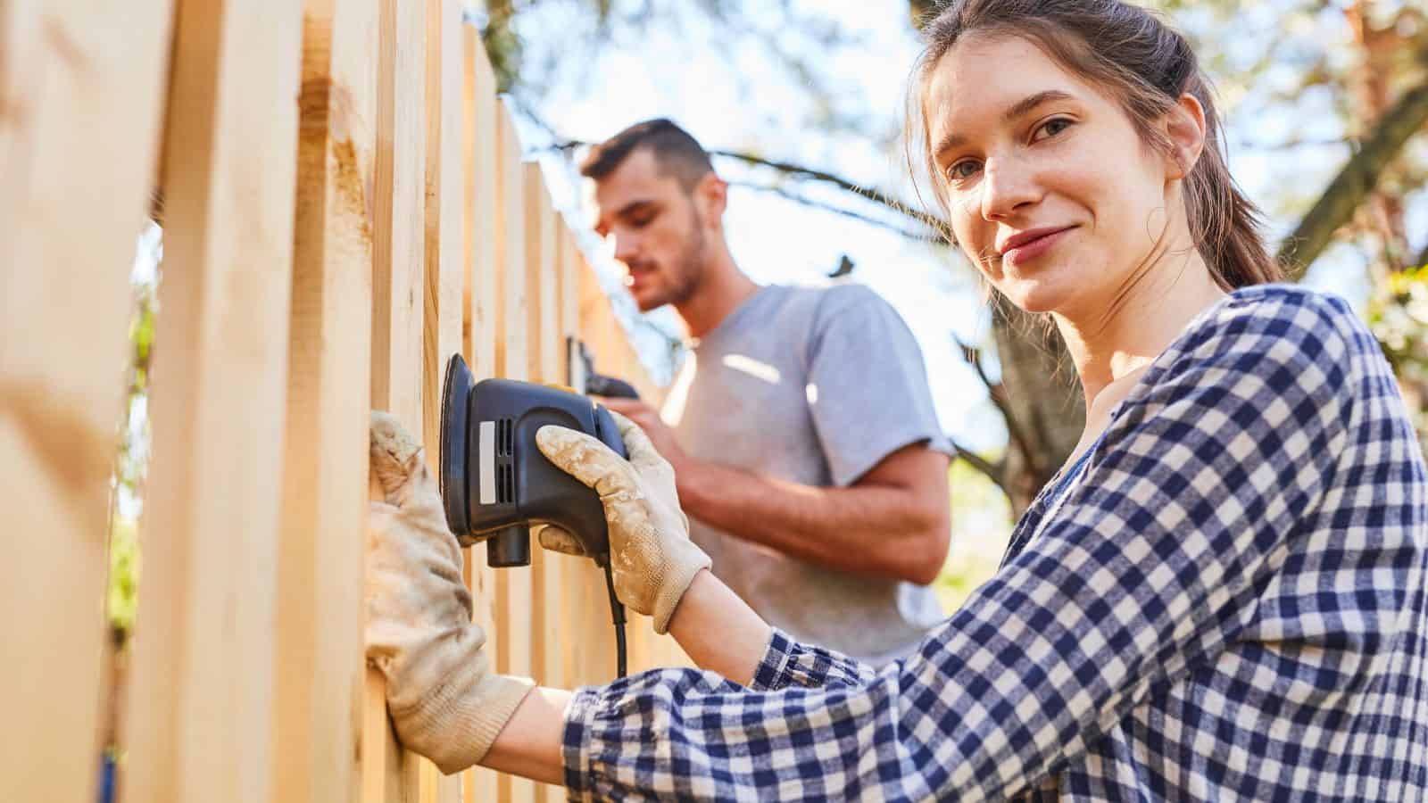 man and woman sanding a fence
