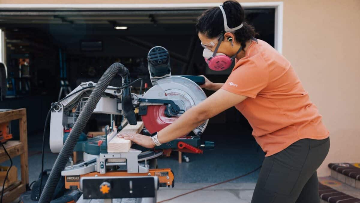Anika wearing safety gear using a miter saw