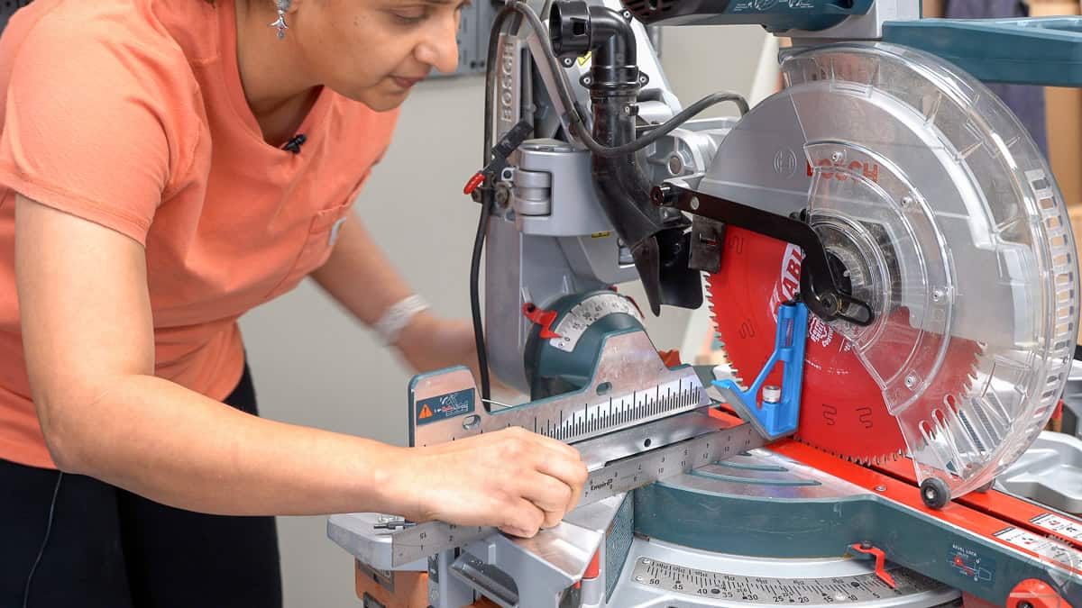 Anika checking the miter saw alignment with the table. This is the bevel adjustment