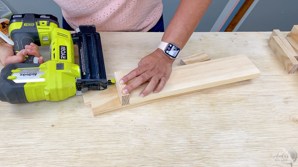 Woman attaching 1x2 boards to the end of the shelf with nail gun.