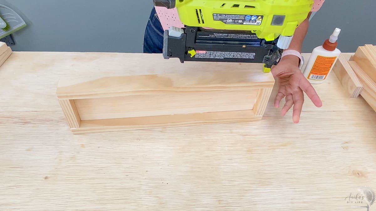 Woman attaching the 1x2 edges of the shelf with a nail gun
