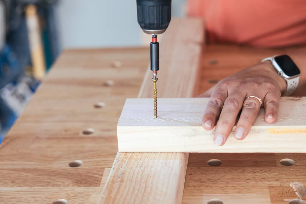 close up of woman driving screw into a 2x4