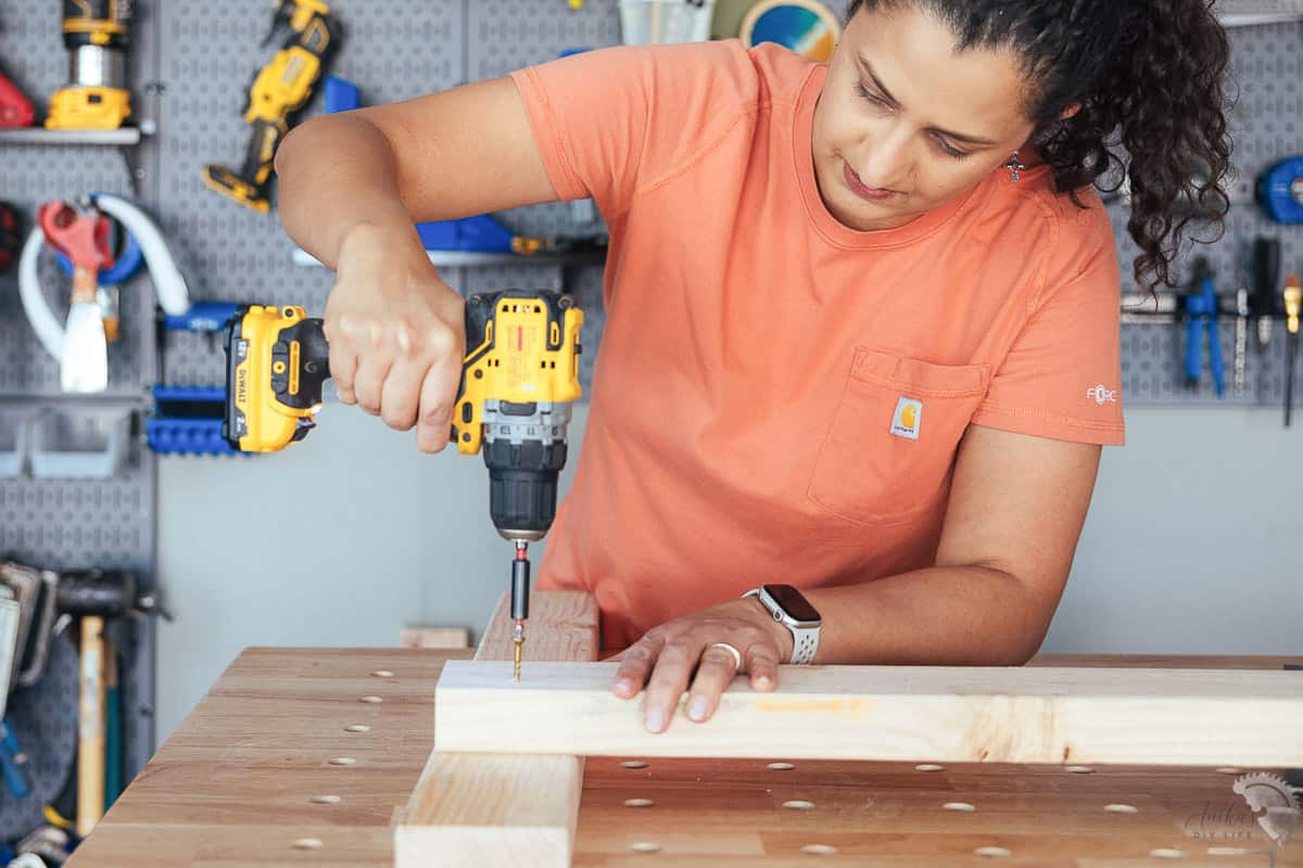 woman using a power drill to drive a screw into wood