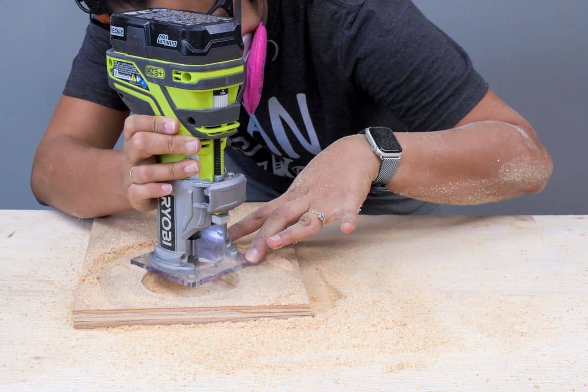 Woman using a router to make a recess in wood