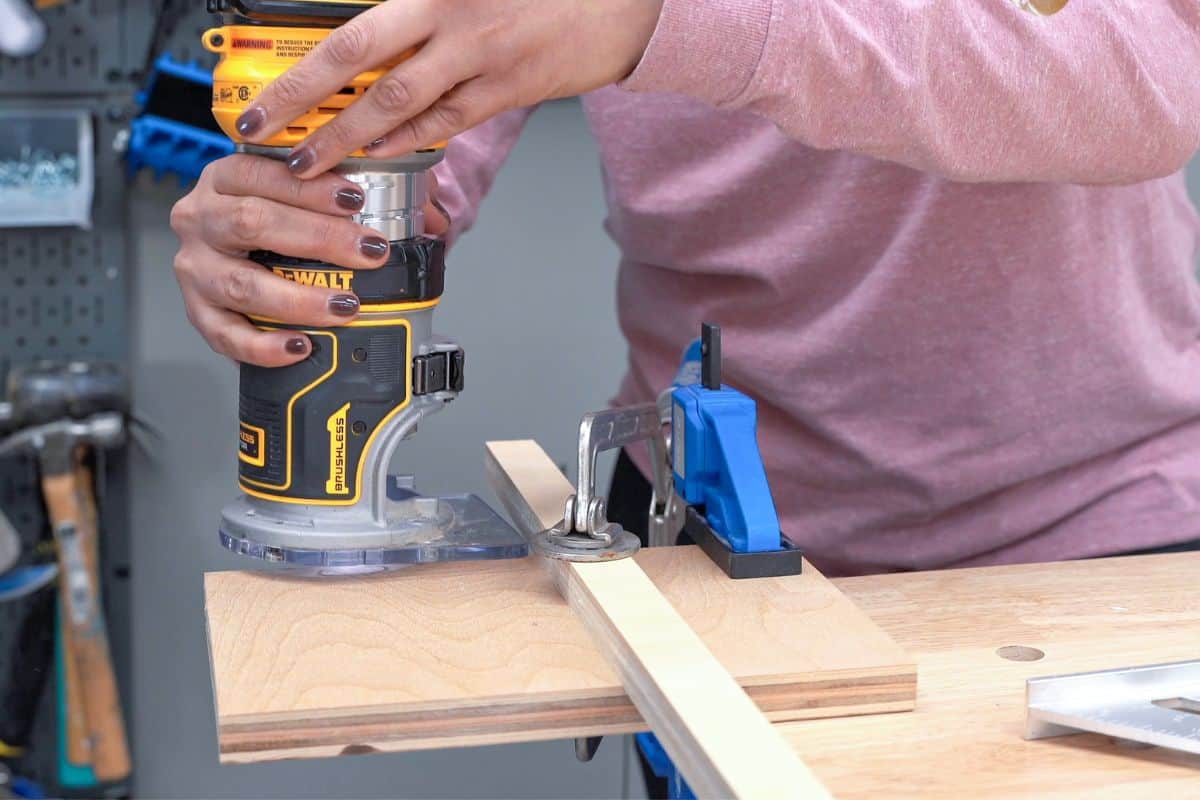 plywood clamped to a workbench and woman getting ready to use a router