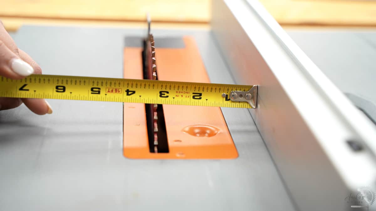 measuring the distance of the rip fence from the blade with a tape measure