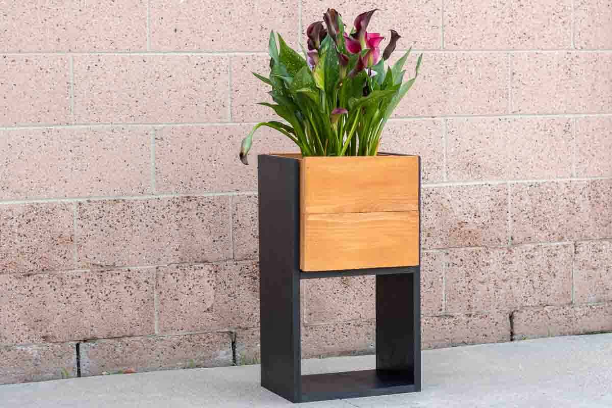 diy tall modern planter with flowers in front of wall.
