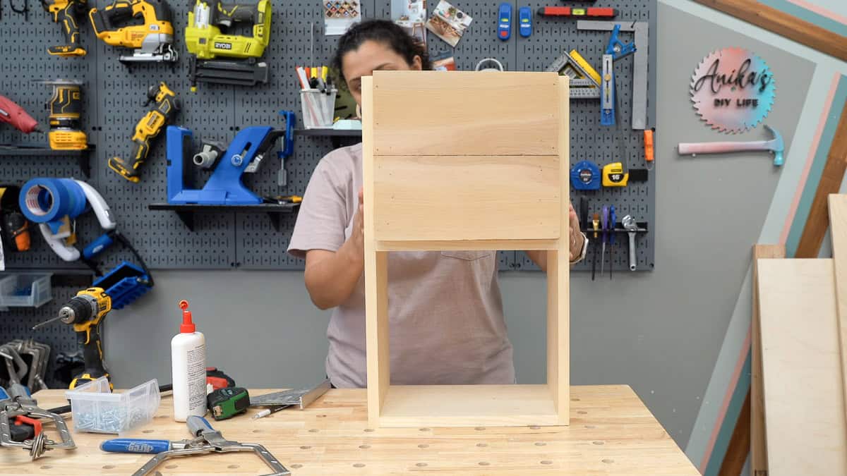 woman fitting the box inside the stand to complete the DIY Tall Modern Planter