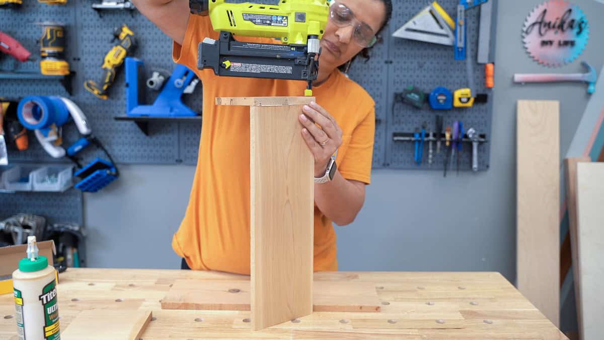 Anika attaching cedar boards with nail gun to build a small wood planter