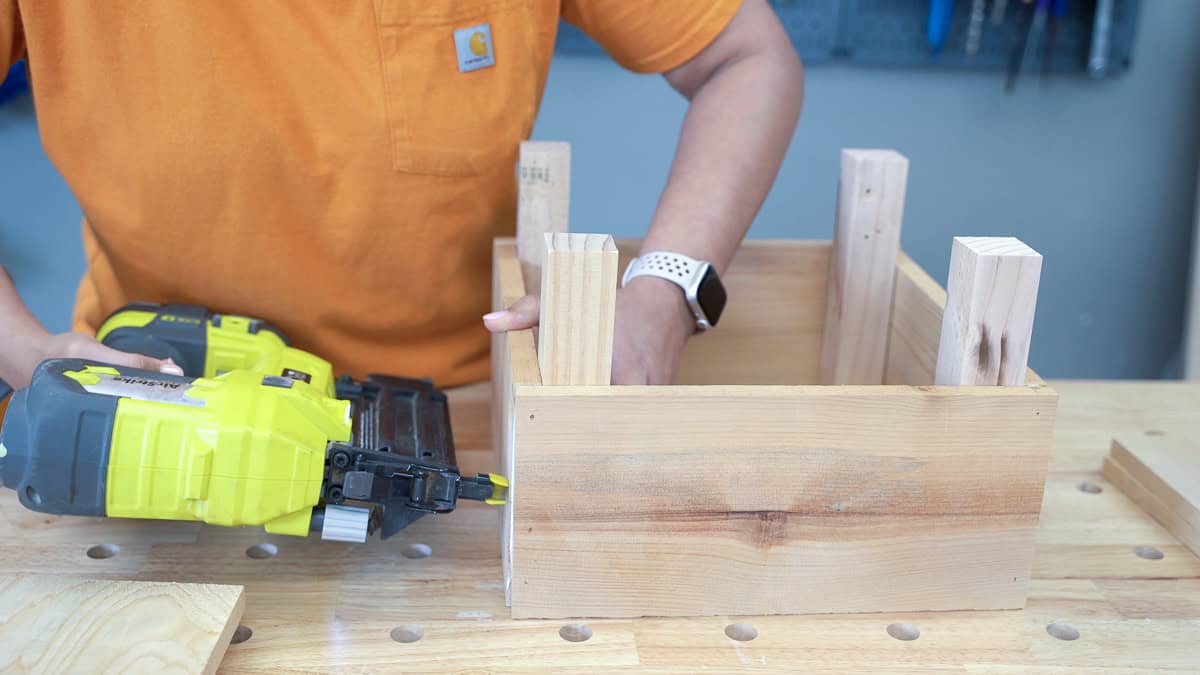 Anika attaching 2x2 supports inside the planter box using nail gun