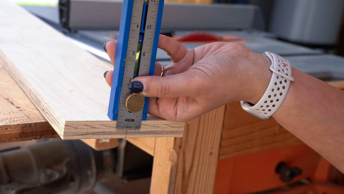 Woman marking the middle of the board using a Kreg multimark tool to make french cleats