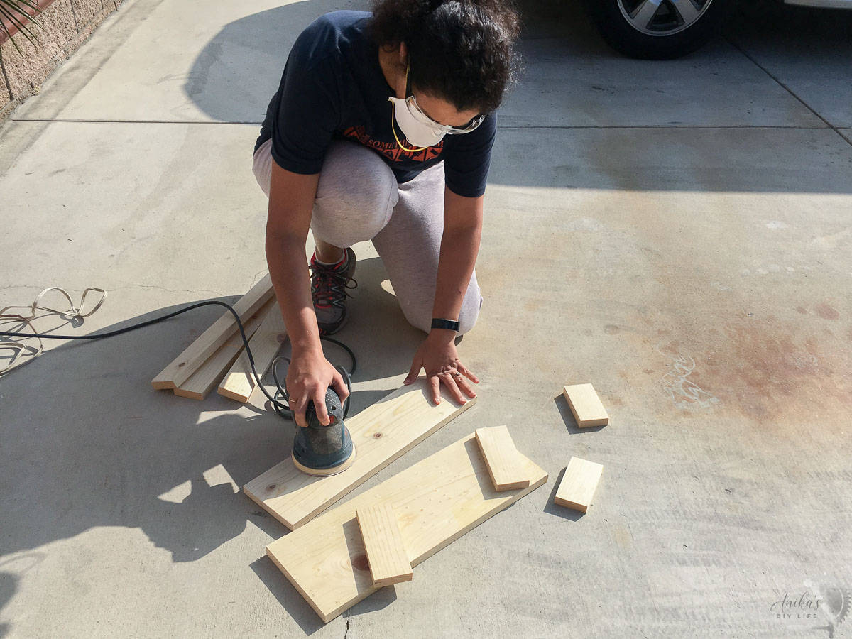 woman sanding boards on the ground