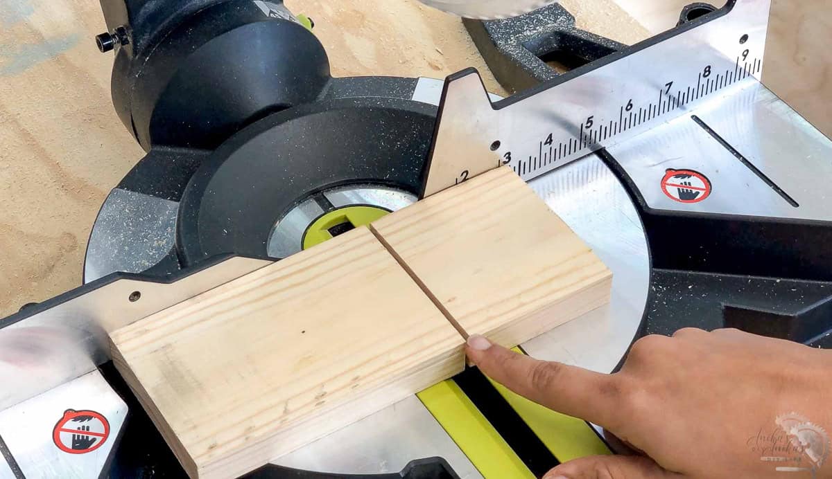 woman pointing to the kerf of the saw blade on a board
