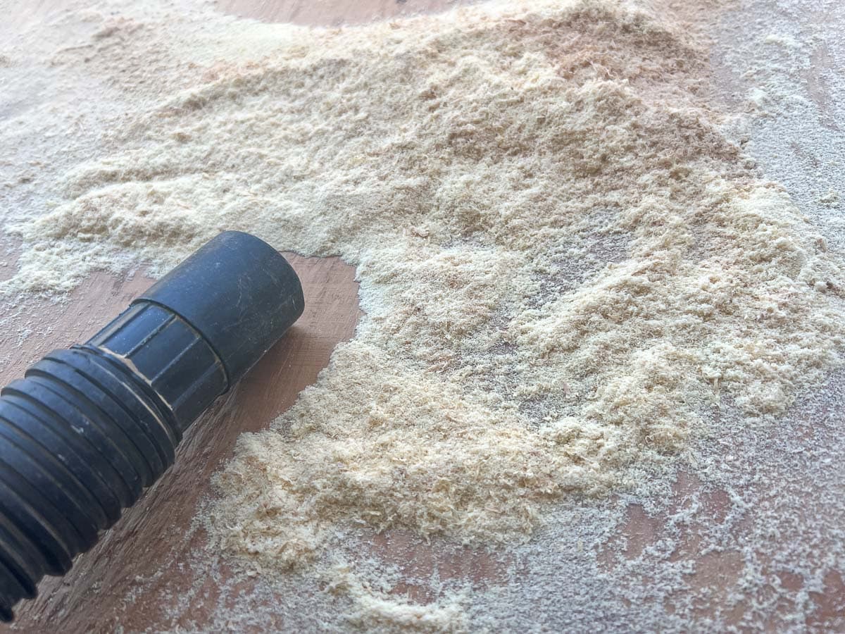 shop vac hose picking up pile of sawdust