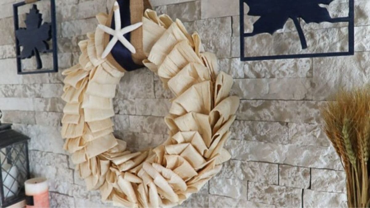 DIY corn husk wreath for fall hanging above a fireplace