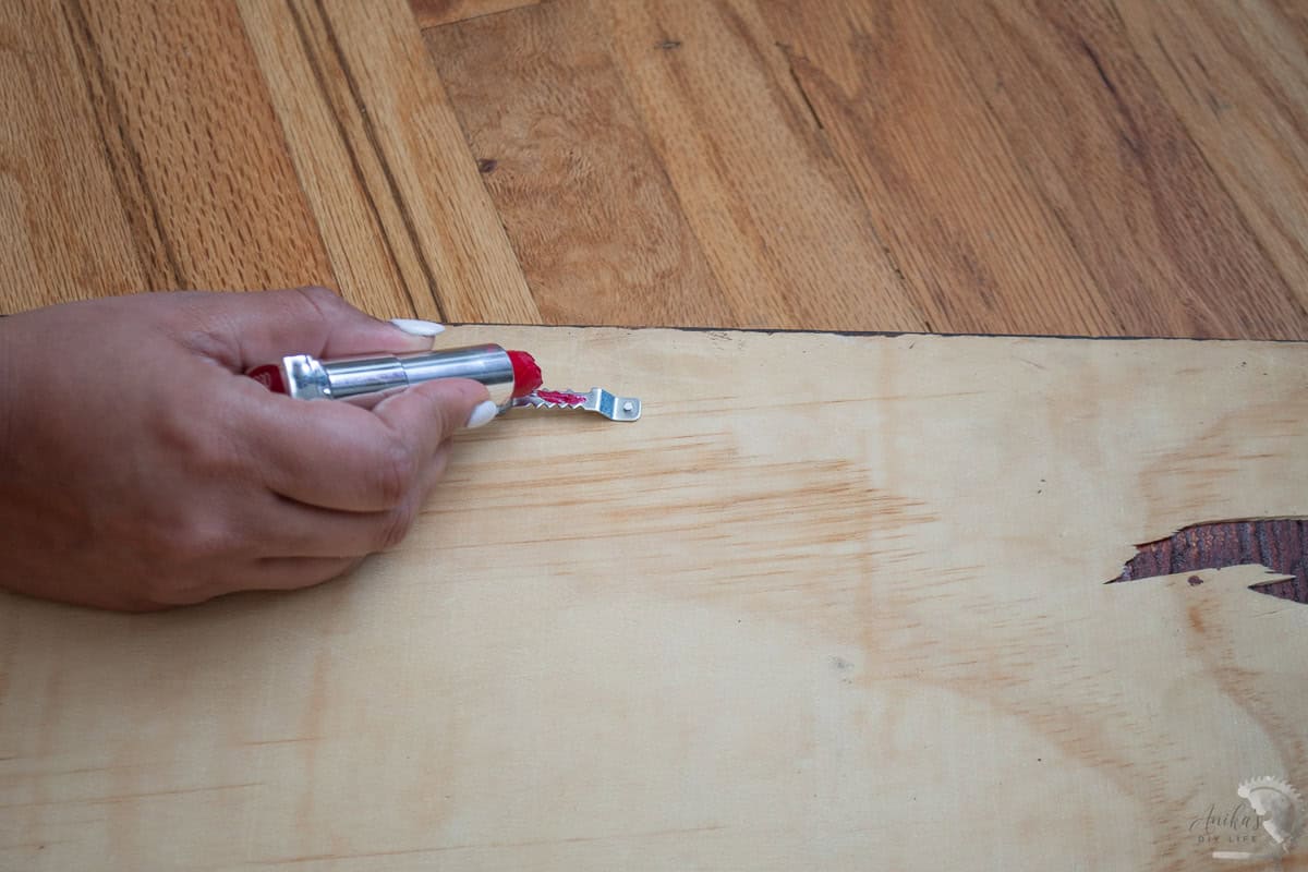 applying lipstick to the hanger to hang picture on the wall.