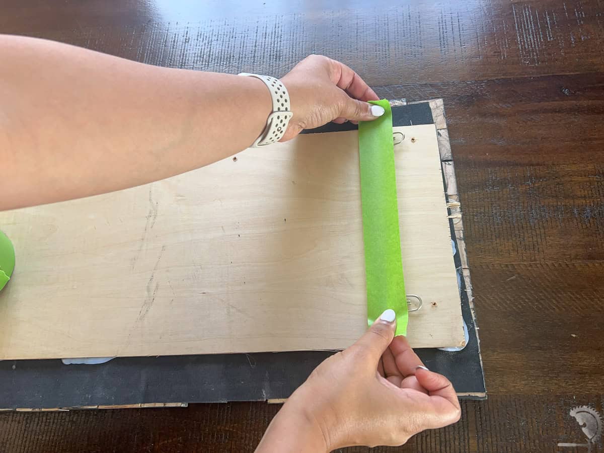 Adding tape to the back of the artwork to hang it on the wall.