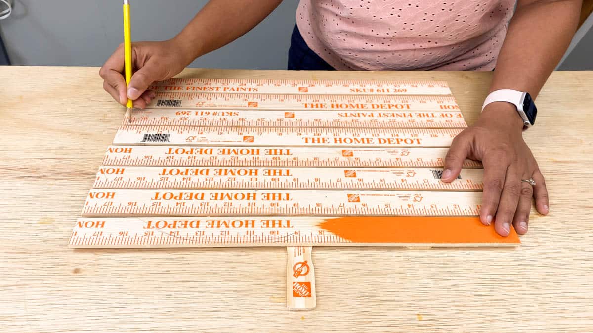Drawing a pumpkin shape on yardsticks for DIY lighted pumpkin