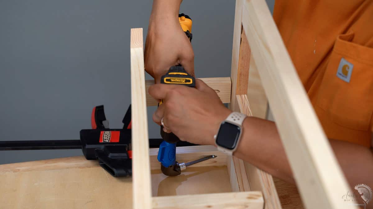 Woman adding pocket hole screws in a tight spot using a right angle drill adapter