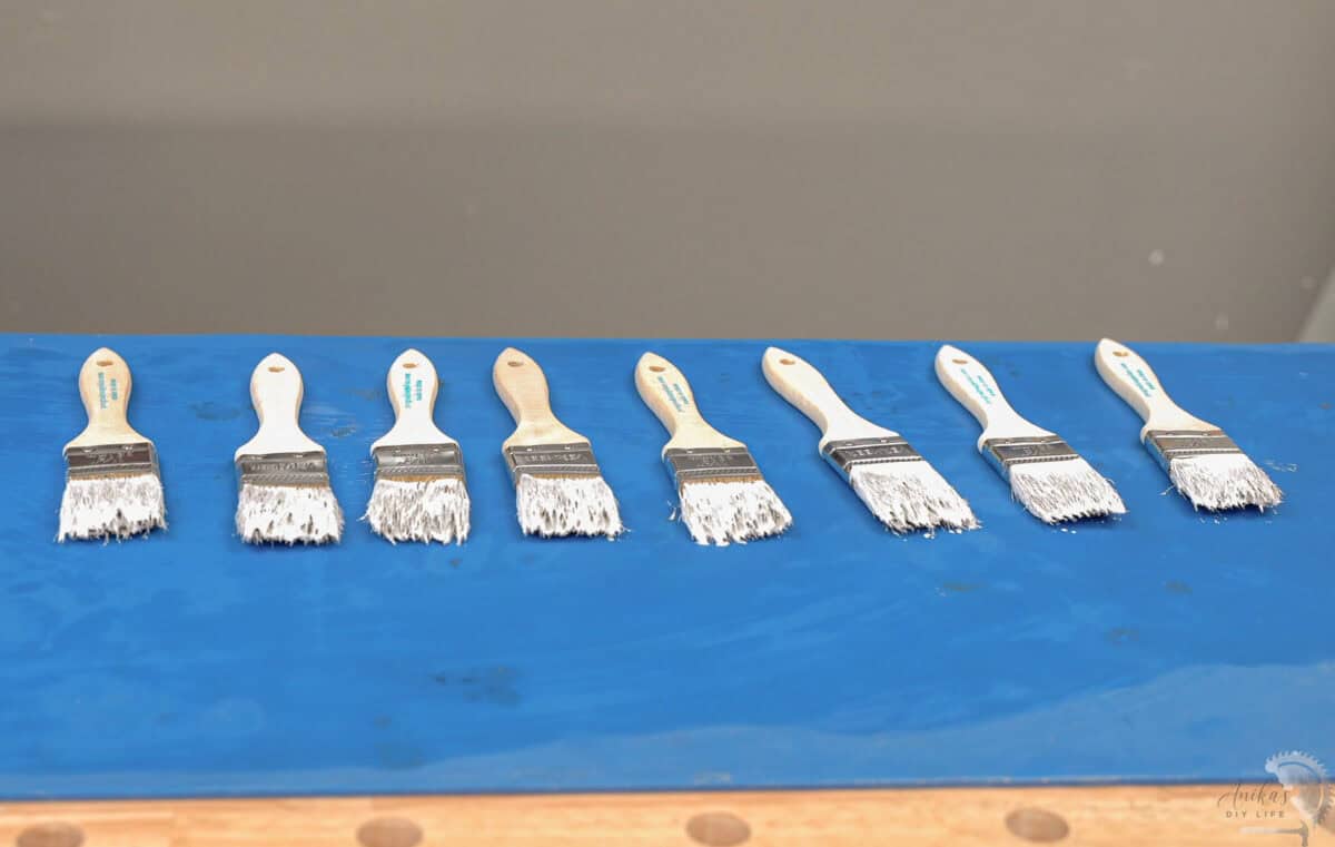 Paint brushes dipped in paint left to dry on a blue silicone mat