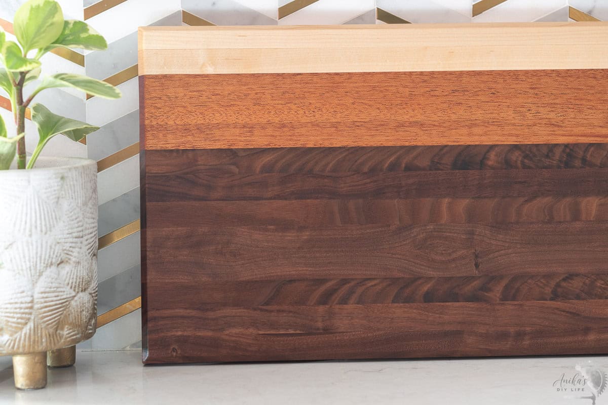 DIY Cutting board with multiple wood types against a kitchen backsplash