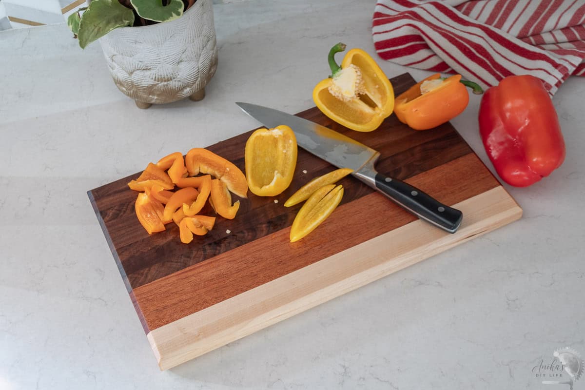 another view of DIY cutting board with multiple wood types on a kitchen counter with bell peppers on it