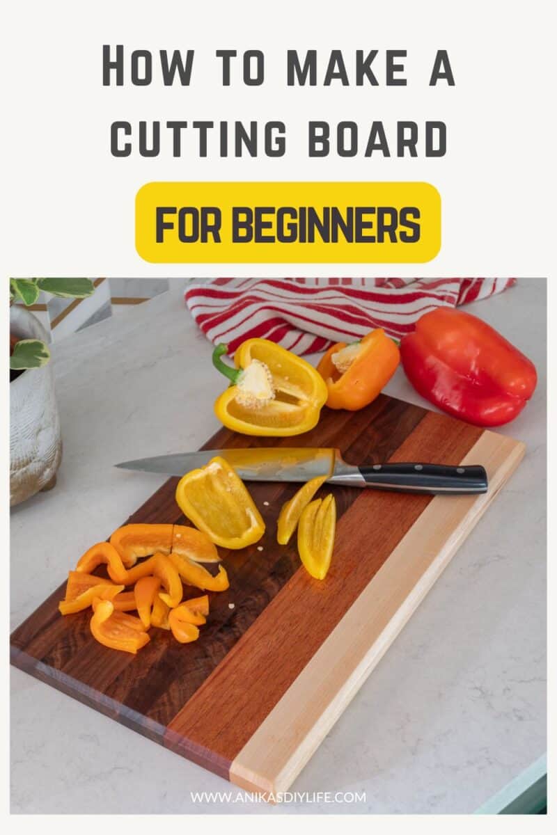 DIY cutting board with multiple wood types on a kitchen counter with bell peppers on it with text overlay - "how to make a cutting board for beginners"