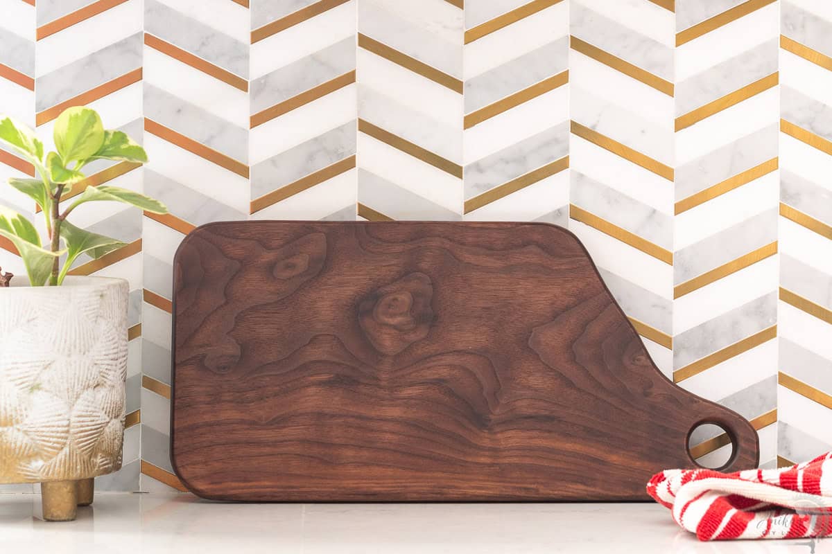 Walnut cutting board against the kitchen backsplash