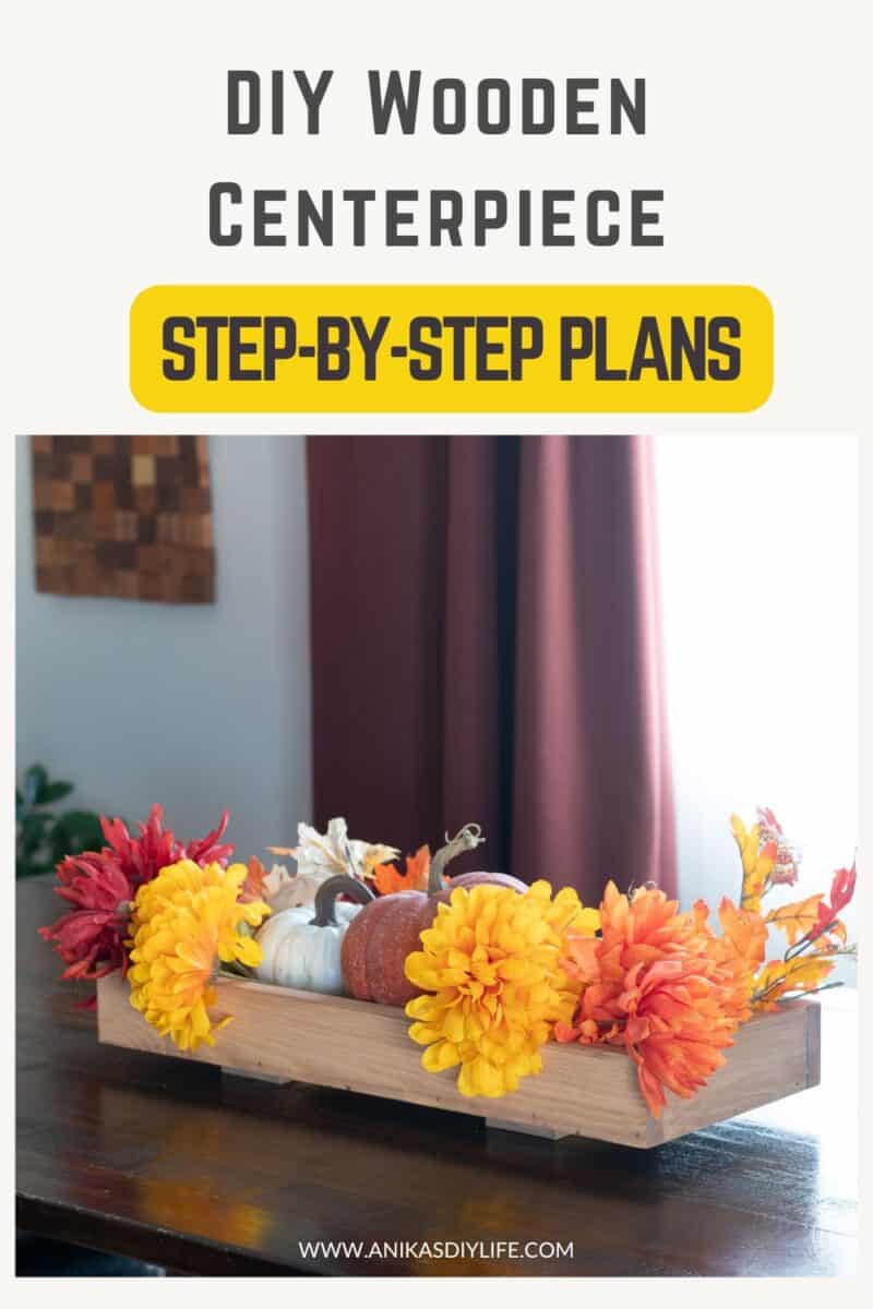 another angle of view of DIY wooden centerpiece decorated with fall flowers and pumpkins on a dining table with text overlay