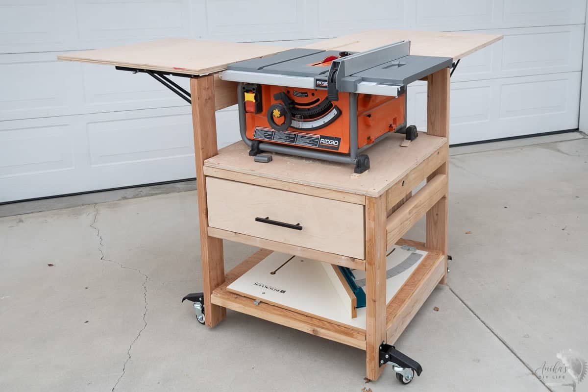 DIY Table saw stand with folding outfeed table and extension wing and storage drawer in driveway